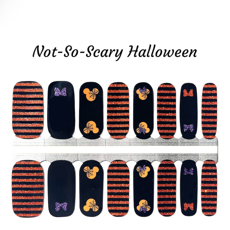 May include: Set of 10 Halloween-themed nail wraps featuring orange and black striped designs, Mickey Mouse heads with spiderwebs, and purple bows. The set is titled "Not-So-Scary Halloween".
