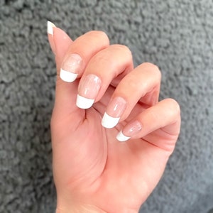 Pode incluir: Uma mão com manicure francesa branca em cada unha.