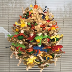 May include: A colorful bird toy made of woven straw, rope, and plastic. The toy features a variety of colors, including green, red, yellow, blue, and orange. It is designed to hang from a ceiling or perch and provides entertainment for birds.
