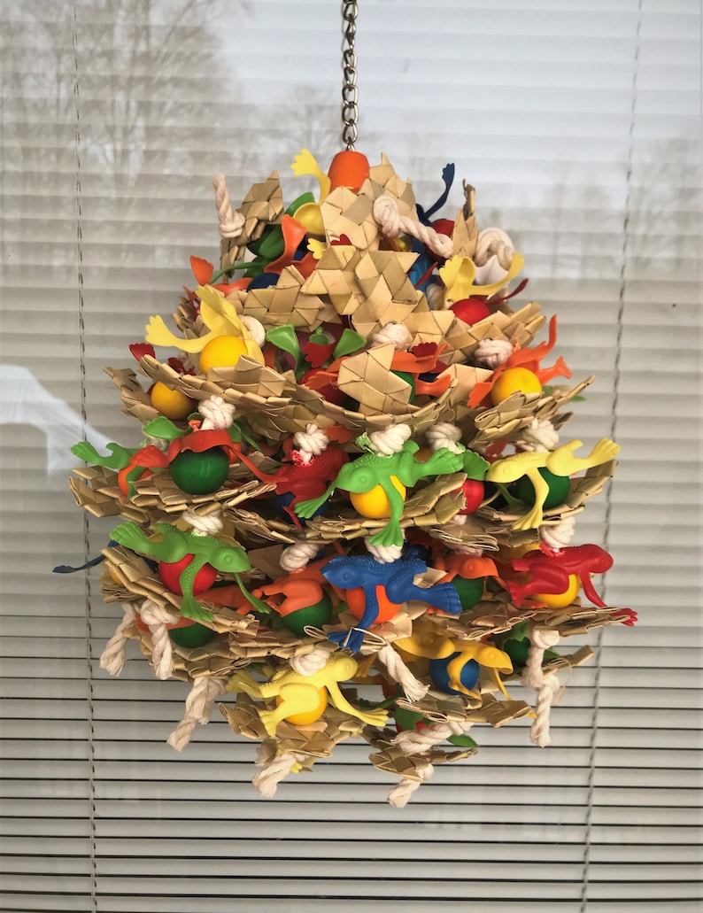 May include: A colorful bird toy made of woven straw, rope, and plastic. The toy features a variety of colors, including green, red, yellow, blue, and orange. It is designed to hang from a ceiling or perch and provides entertainment for birds.