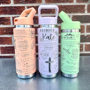 Puede incluir: Tres botellas de agua aisladas de acero inoxidable en melocotón, lavanda y verde menta. Cada botella presenta un diseño diferente con texto inspirador y una cruz. La botella melocotón dice "fearfully and wonderfully made". La botella lavanda dice "Rejoice Kate". La botella verde menta dice "faith can move mountains."