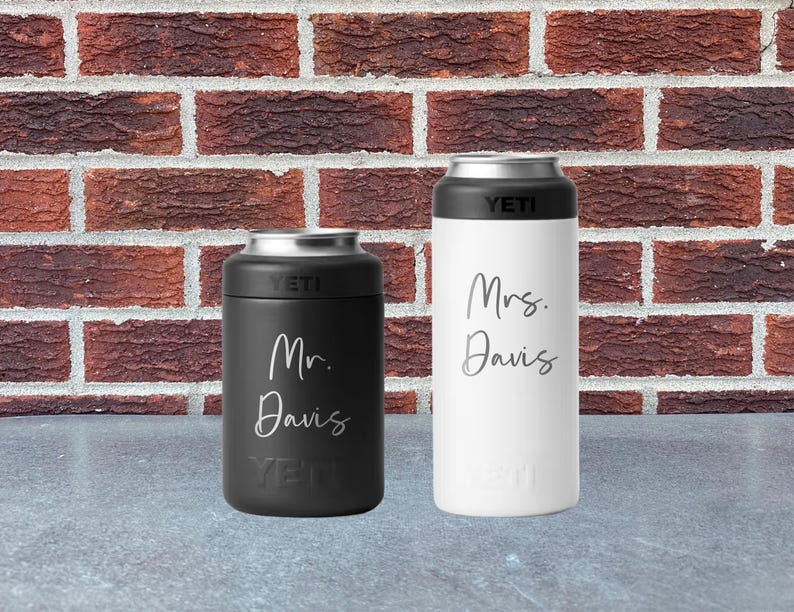 May include: Two insulated beverage holders, one black and one white, with silver tops. The black holder has "Mr. Davis" in script, and the white holder has "Mrs. Davis". Both have the "YETI" logo.