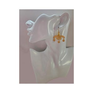 May include: Gold dangle earrings with a floral design. The earrings have a small, round, floral-shaped pendant hanging from the bottom of the main design.