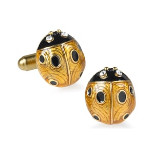 May include: A pair of gold-tone cufflinks with a black and gold ladybug design. The ladybugs have black spots and clear rhinestones on their backs.