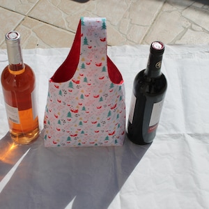 Peut inclure: Un sac fourre-tout à vin à motifs avec un intérieur rouge, flanqué de deux bouteilles de vin. L'une est de couleur rosé, l'autre est sombre avec un bouchon argenté. Le sac présente un motif festif avec des arbres et des animaux.