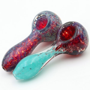 May include: Two glass smoking pipes with colorful, speckled designs. One pipe is red and blue, the other is turquoise and red.
