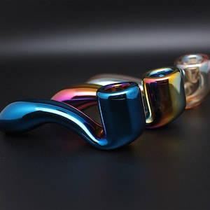 May include: Three iridescent glass smoking pipes, one blue, one green, and one purple, with a curved design.