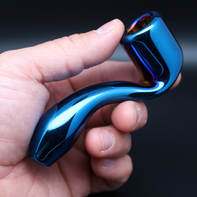 May include: A blue glass pipe with a curved design. The pipe has a shiny, iridescent finish.