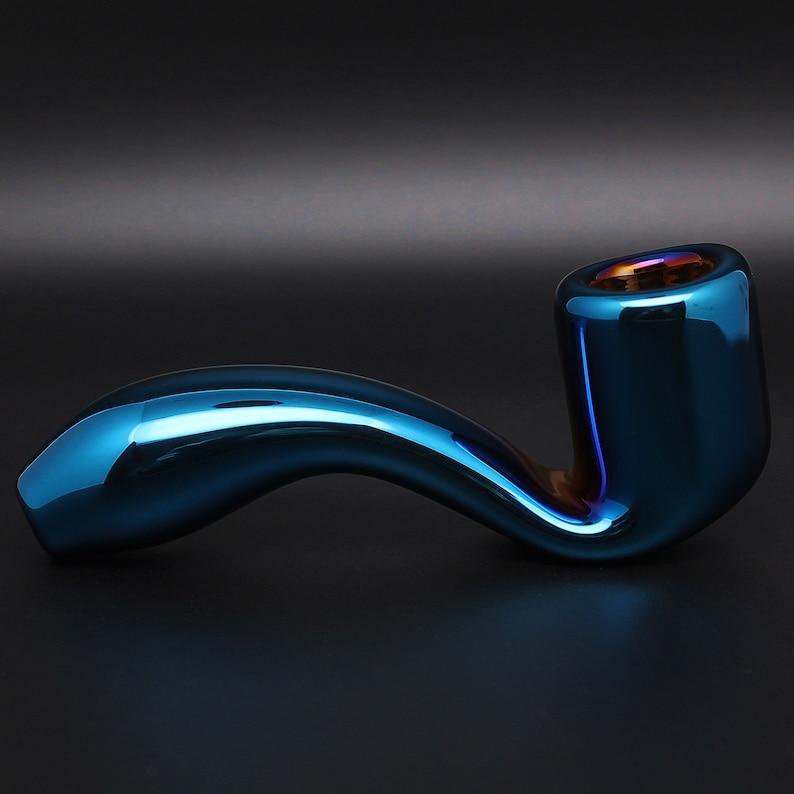 May include: A blue glass pipe with a curved stem and a round bowl. The pipe has a metallic sheen and a slight iridescent effect.