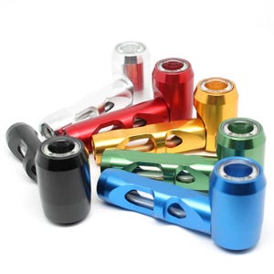 Puede incluir: Un surtido de piezas metálicas de colores, incluyendo negro, plata, rojo, dorado, verde y azul. Cada pieza tiene un cuerpo cilíndrico con un agujero y una pieza de conexión. Las piezas están dispuestas sobre un fondo blanco.