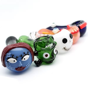 May include: Five glass pipes with different cartoon character faces. The pipes are green, blue, white, orange, and red.
