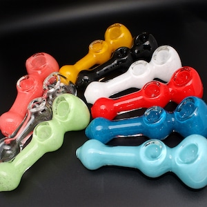 May include: A collection of ten glass smoking pipes in various colors, including red, blue, green, yellow, white, and black. The pipes are all made of glass and have a simple design.