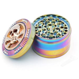 May include: A rainbow-colored grinder with a skull and crossbones design on the lid. The lid is adorned with clear rhinestones. The grinder is made of metal and has a multi-colored finish.