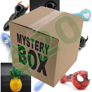 May include: A brown cardboard box with the words "MYSTERY BOX" printed on the front. The box is surrounded by various colorful glass pipes, including a red and black pipe with horns, a blue pipe with a heart, a green pipe with flowers, a yellow pipe shaped like a pineapple, a blue pipe, and a red and black pipe with a Spiderman design.