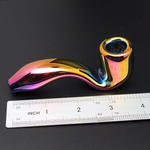 May include: A rainbow iridescent glass pipe with a curved stem and a bowl. The pipe is about 3 inches long and is measured against a ruler.