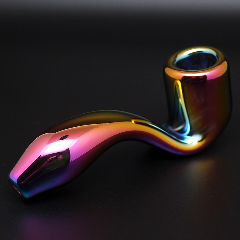May include: A iridescent glass pipe with a curved stem and a round bowl. The pipe has a rainbow finish with shades of purple, blue, green, and red.