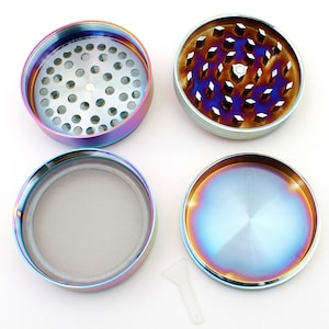 May include: A disassembled, multi-piece grinder with a rainbow iridescent finish. The grinder is round, with a silver-colored interior and a mesh screen. A small, clear plastic scraper is included. The grinder is designed for herbs.