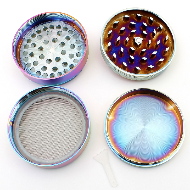 May include: A disassembled, multi-piece grinder with a rainbow iridescent finish. The grinder is round, with a silver-colored interior and a mesh screen. A small, clear plastic scraper is included. The grinder is designed for herbs.