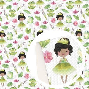 May include: White fabric with a repeating pattern of a cartoon princess, frogs, lily pads, and pink flowers. The princess wears a green dress and a crown. The frogs are green.