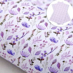 Peut inclure: Tissu en simili cuir blanc avec un motif répété de fleurs et de feuilles violettes.