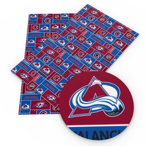 May include: A red and blue fabric with a repeating pattern of the Colorado Avalanche logo. The logo features a stylised 'A' with a blue wave design. The fabric is ideal for crafting projects.