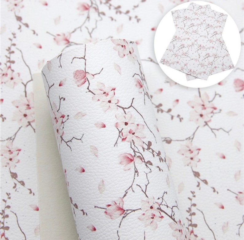 May include: White faux leather with a pink floral pattern. The flowers are delicate and have a watercolor effect. The background is a textured white.