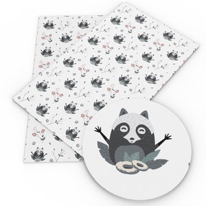 May include: White fabric with a repeating pattern of gray raccoons and pink flowers. A separate white circle with a gray raccoon with black eyes and a black nose, surrounded by green leaves.