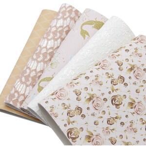 Peut inclure: Quatre feuilles de simili cuir avec différents motifs. Les motifs comprennent une sirène avec des paillettes dorées, un motif floral avec des accents dorés, un motif de dentelle et un motif géométrique.