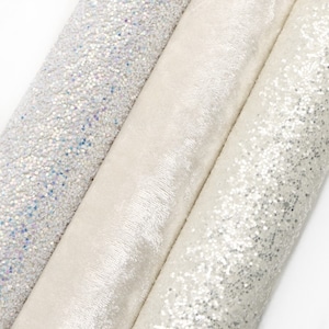May include: Three rolls of white fabric with glitter. The fabric on the left has iridescent glitter, the fabric in the middle is smooth, and the fabric on the right has silver glitter.