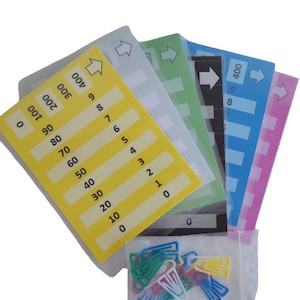 May include: A set of six colorful number cards with arrows pointing to the right. The cards are yellow, green, light blue, dark blue, pink, and white. The numbers on the cards range from 0 to 400. The cards are arranged in a fan shape with the yellow card on top. A small bag of colorful paper clips is in the lower right corner of the image.