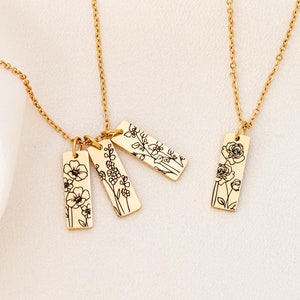 May include: Three gold necklaces with delicate chains and rectangular pendants featuring floral designs. The pendants are engraved with different floral patterns, including roses, wildflowers, and a single flower.