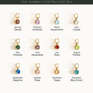 May include: A collection of 12 birthstone charms, each with a 6mm gemstone in a gold setting. The charms are labeled with the month and stone name, including Garnet, Amethyst, Aquamarine, and Crystal. The text reads "BIRTH STONE CHARMS".