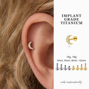 May include: Gold-colored crescent moon earring with white and clear stones. The earring is shown on an ear. The image includes the text "IMPLANT GRADE TITANIUM" and "sold individually". Sizes available: 5mm, 6mm, 8mm, 10mm.
