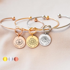 May include: Three gold, silver, and rose gold bangle bracelets with a knot design and a round charm with a flower and personalized text. The charms read "Lillianne - 08/25/21", "Samantha - 01/20/20", and "Kourtney - 10/28/22".