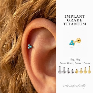 Könnte beinhalten: Ein goldfarbener Ohrpiercing aus Titan mit drei kleinen, türkis farbenen Steinen. Das Bild enthält den Text „IMPLANT GRADE TITANIUM“ und „sold individually“. Das Piercing wird in verschiedenen Größen gezeigt, darunter 5 mm, 6 mm, 8 mm und 10 mm.
