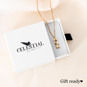 May include: Gold necklace with a delicate floral design pendant in a white gift box. The box has the logo "CELESTIAL by ABJ" printed on it.