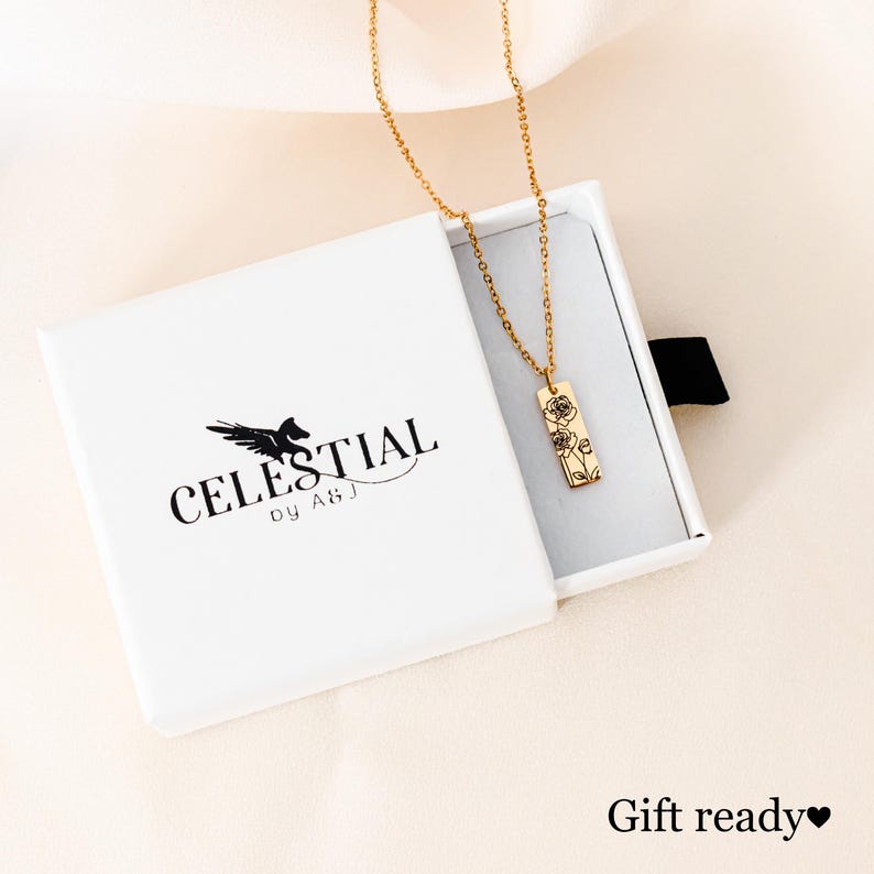 May include: Gold necklace with a delicate floral design pendant in a white gift box. The box has the logo "CELESTIAL by ABJ" printed on it.