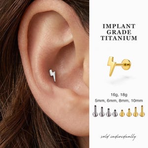 May include: A silver lightning bolt stud earring is shown in an ear piercing. The image also displays a gold lightning bolt stud earring. Text reads "IMPLANT GRADE TITANIUM" and "16g, 18g" with sizes 5mm, 6mm, 8mm, and 10mm. The text "sold individually" is also present.