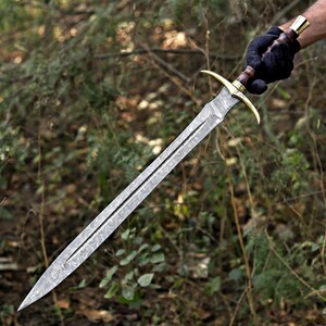 May include: A double-edged sword featuring a patterned Damascus steel blade, a brass crossguard, and a dark wooden handle with a brass pommel. The blade displays a distinct wavy, layered metal texture running along its length to a sharp point.