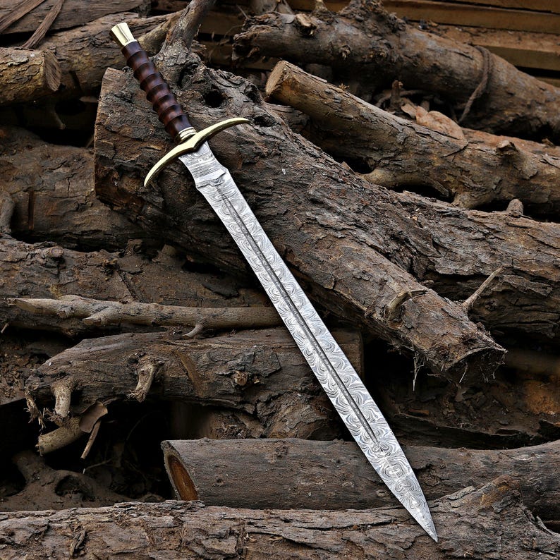 May include: A sword with a patterned Damascus steel blade, a brass crossguard, and a dark brown ridged wooden handle. The blade features a central fuller and a sharp point, while the hilt includes a brass pommel cap at the end.