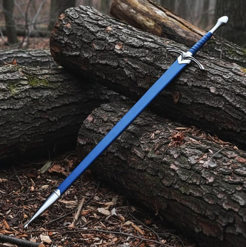 May include: A long sword with a blue scabbard and a matching blue wrapped handle. The sword features a silver-colored metal crossguard and a pointed pommel. The scabbard is finished with a silver-colored metal tip at the bottom end.