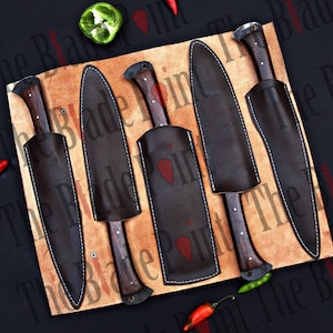 Pu&ograve; includere: Cinque fodere in pelle marrone con cuciture sui bordi, ciascuna contenente un coltello di colore scuro con manico in legno. Le fodere sono disposte in fila su una superficie marrone chiaro.