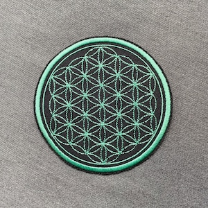 Könnte beinhalten: Ein gestickter Patch in Grün und Schwarz mit einem geometrischen Muster, das als Blume des Lebens bekannt ist.
