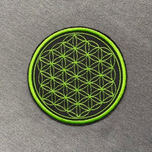Peut inclure: Un patch brodé noir et vert avec un motif géométrique de la fleur de vie.