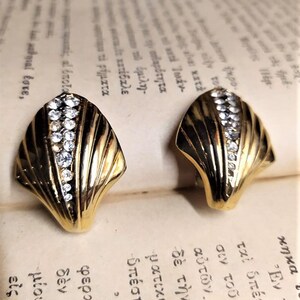 May include: A pair of gold tone clip-on earrings with a shell design and clear rhinestones.