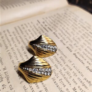 May include: A pair of gold tone earrings with a fan-shaped design and clear rhinestones.
