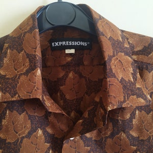Puede incluir: Una camisa marr&oacute;n de botones con un estampado de hojas doradas. La camisa tiene cuello y una etiqueta que dice "EXPRESSIONS".