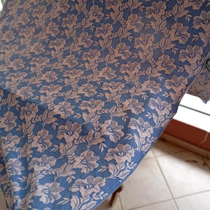 May include: A blue fabric with a white floral pattern. The fabric is folded and draped over a chair.