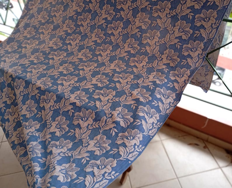 May include: A blue fabric with a white floral pattern. The fabric is folded and draped over a chair.