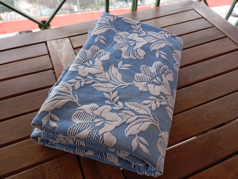 May include: A folded blue fabric with a white floral pattern. The fabric is textured and has a slightly raised design.